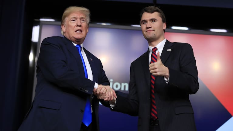 President Donald Trump shakes hands with moderator Charlie Kirk during a Generation Next White House forum in 2018.