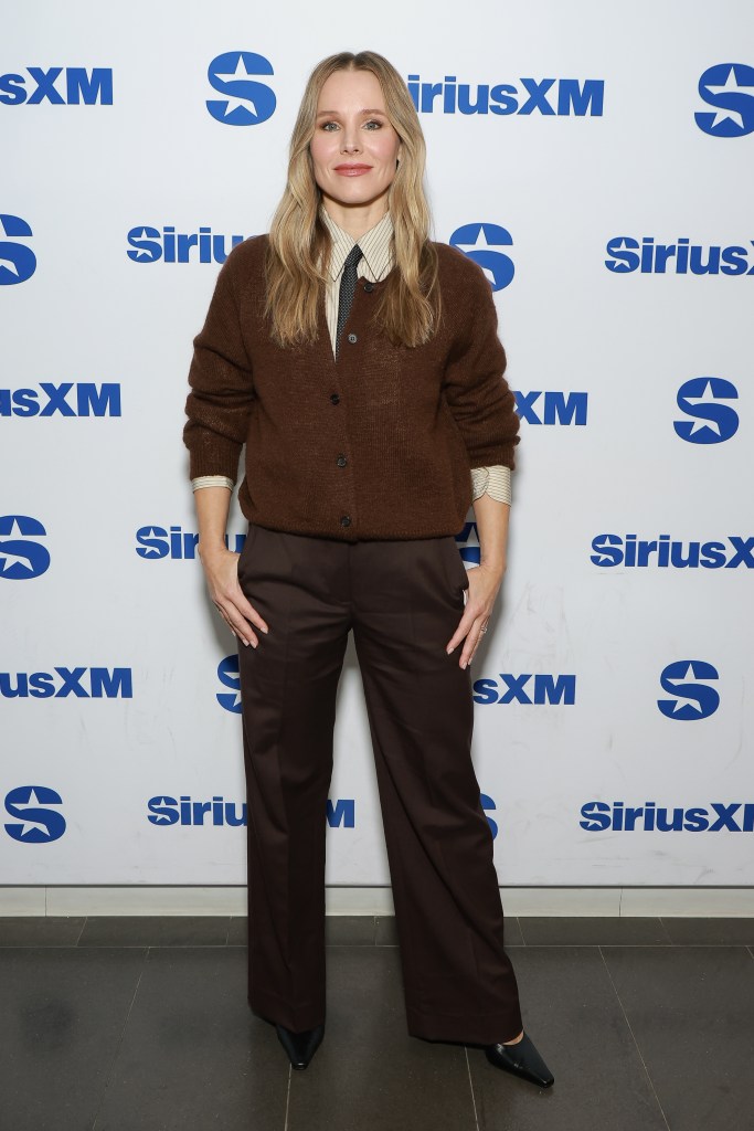 Kristen Bell poses in a brown cardigan over a striped shirt with patterned tie.